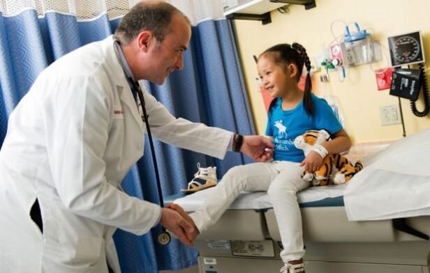 një mjek ekzaminon një fëmijë me artrozë të ijeve